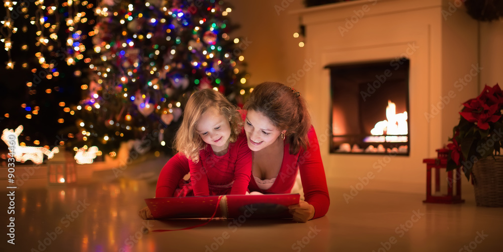 Mother and daughter reading at fire place on Christmas eve Mother and daughter reading at fire place on Christmas eve
