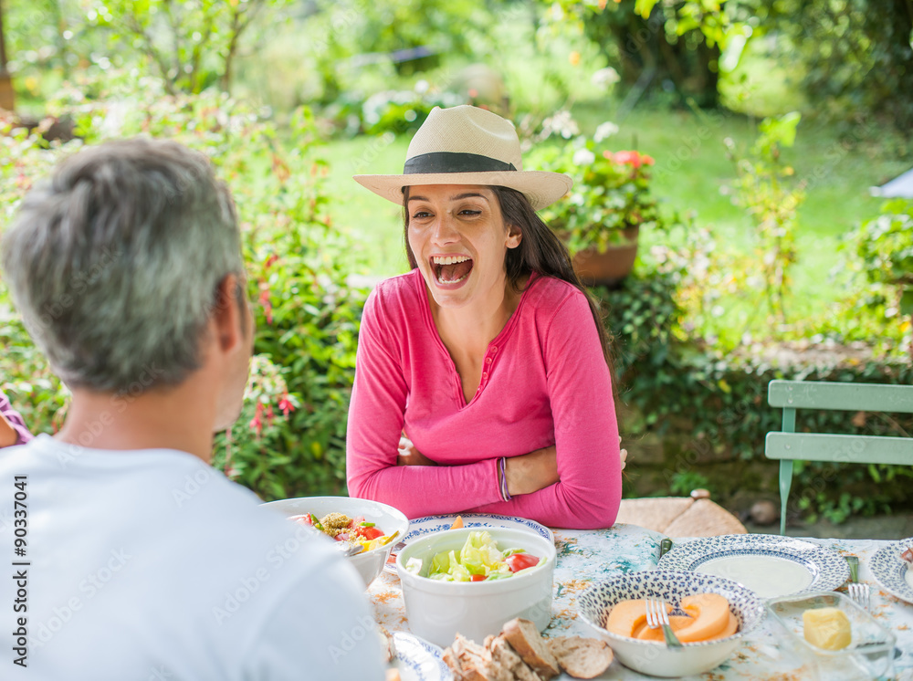 Good joke ! Couple laughing during a garden lunch