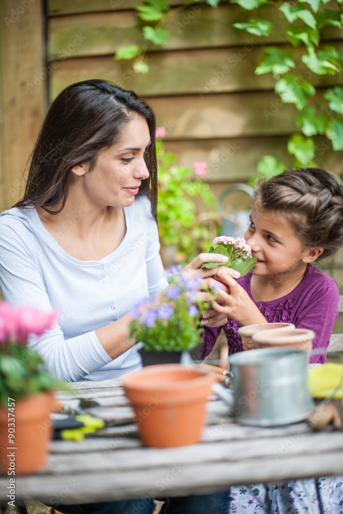 mother and daughter are repotting plants at the garden table