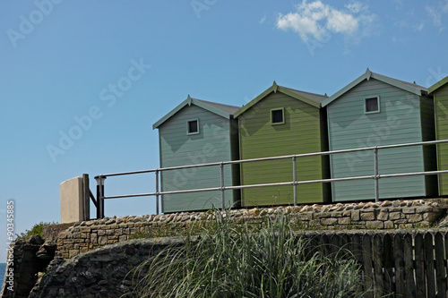 A bunch of green beach huts, blue sky, summer holidays