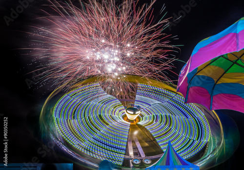Firework and amusement ride under one umbrella. Long exposure to show fireworks and motion for the ride.