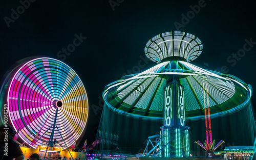 Giant Ferris Wheel and Yo-Yo amusement ride side by side in night time shot with long exposure.