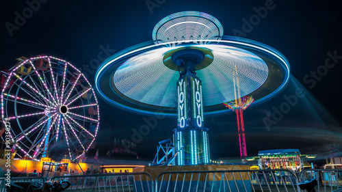 Giant Ferris Wheel and Yo-Yo amusement ride side by side in night time shot with long exposure.