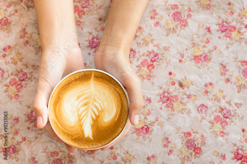 Vintage woman hands holding latte art coffee mug on flower vinta