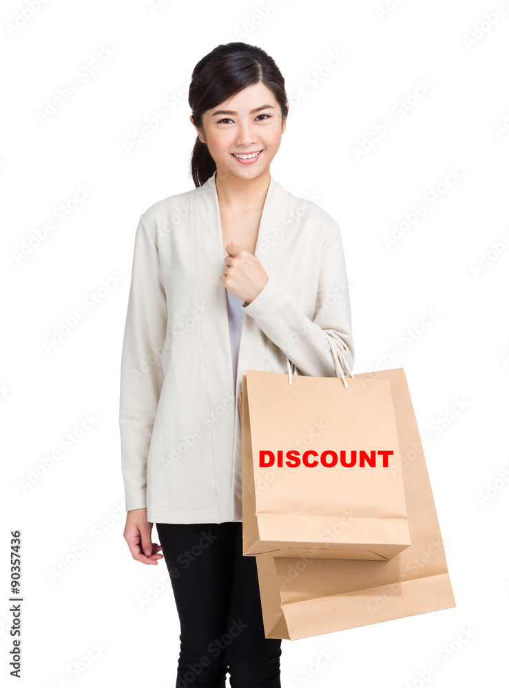 Young woman holding shopping bag and showing a word discount Young woman holding shopping bag and showing a word discount