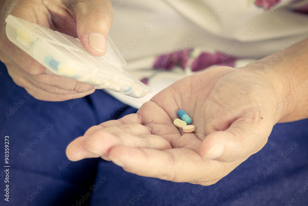old woman hand pouring pills from a pill reminder box into her h old woman hand pouring pills from a pill reminder box into her h