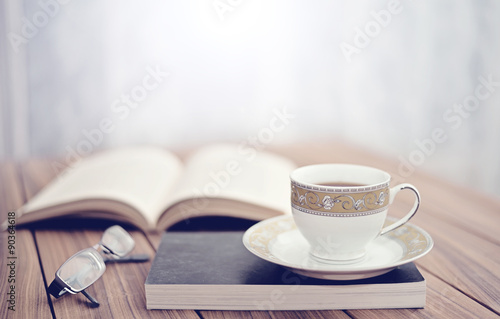 Book and tea/coffee on a wooden table