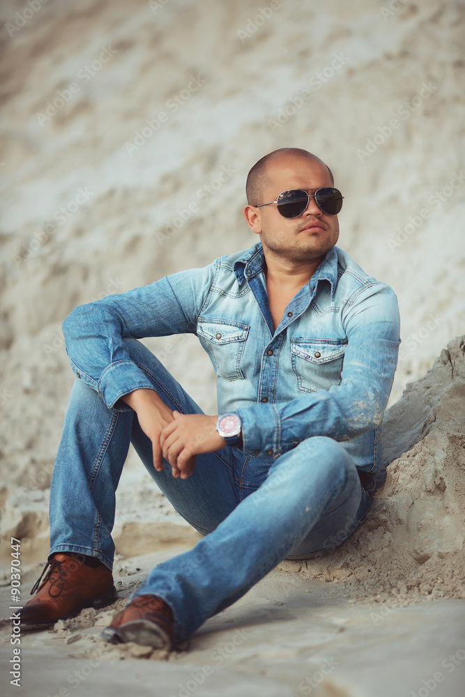adult man lying in jeans clothes in the sand in Thailand