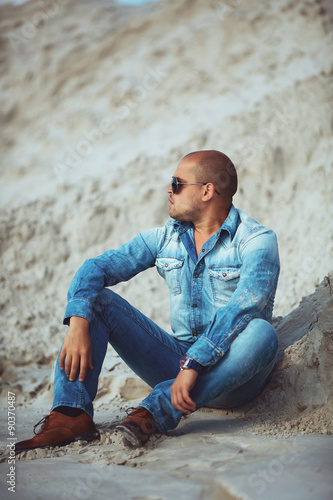 adult man lying in jeans clothes in the sand in Brazil
