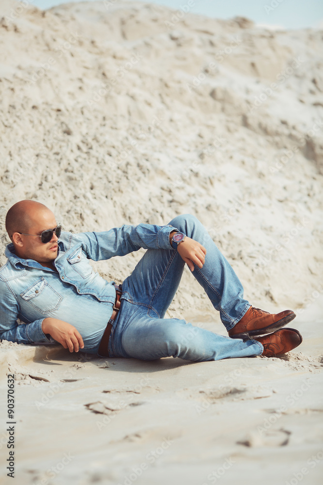 Fashionable stylish man lying on the sand Fashionable stylish man lying on the sand