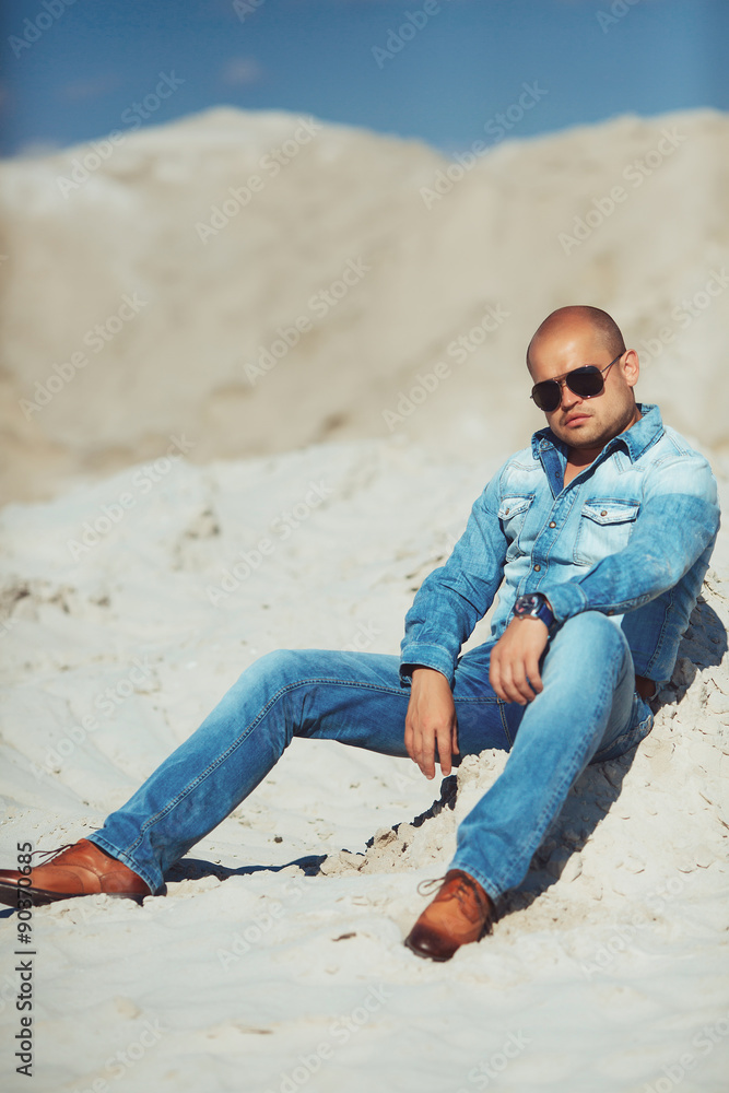 brutal man sitting on the sand, bronzed brutal man sitting on the sand, bronzed