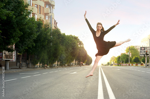 a young dancer jumping on a background the road, trees and morni