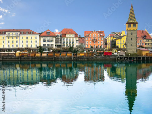 Harbour promenade in Lindau with reflection in the water in the sunny day. Tower Mangenturm. Bavaria, Germany, Europe.