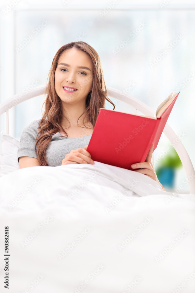 Woman lying in a bed and holding a book Woman lying in a bed and holding a book