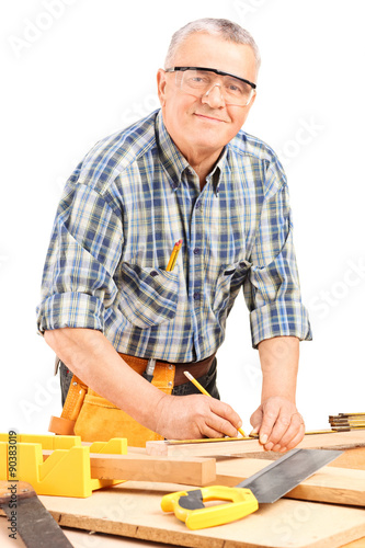 Mature carpenter measuring a plank