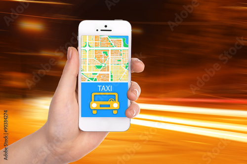 Hand holding mobile smart phone with interface taxi on night background photo