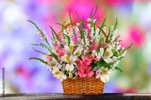 Beautiful wildflowers in wicker basket on abstract background