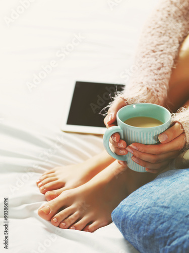 Woman using tablet at cozy home atmosphere on the bed. Young bea