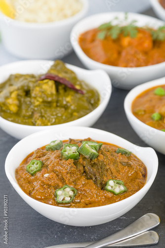 Bhindi Masala - Spiced okra in thick gravy. Chapattis and other vegetarian curries on background.
