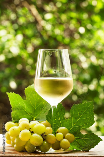 Coid white wine and green grapes on natural blurred background w photo