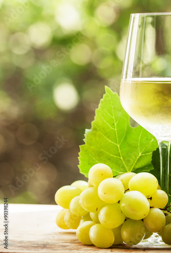 Coid white wine and green grapes on natural blurred background w photo