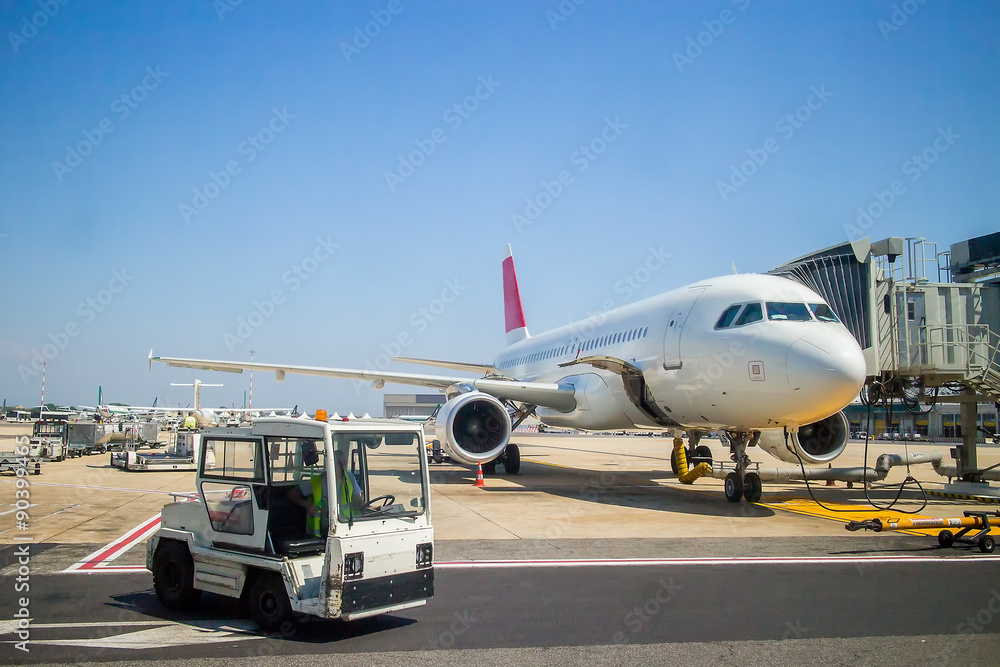 plane at the airport during loading passengers. near the tractor