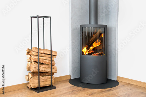 Φωτογραφία Fire and flames in a modern burning stove next to a wood logs rack, contemporary