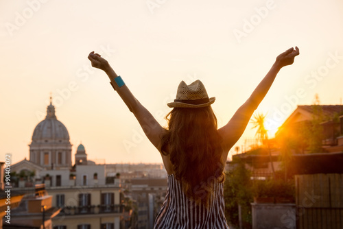 Billede på lærred Woman from behind with outstretched arms in Rome at sunset