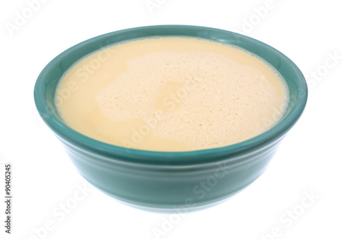 Bowl of evaporated milk on a white background.