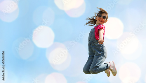 happy little girl jumping high over blue lights