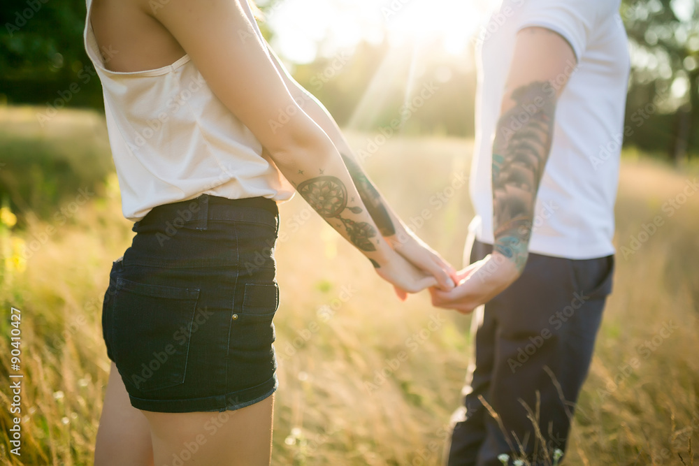 A man and a girl with a tattoo on the nature holding hands A man and a girl with a tattoo on the nature holding hands
