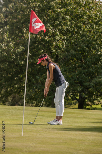 Portrait of a young woman swinging her club on a golf course.