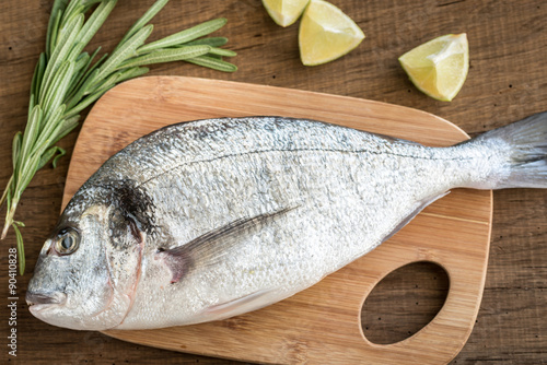 Fresh dorada with ingredients on the wooden board photo