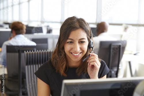 Young woman working in a call centre, holding headset