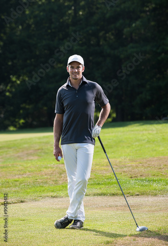 Close up of a handsome golfer holding a ball on the green during