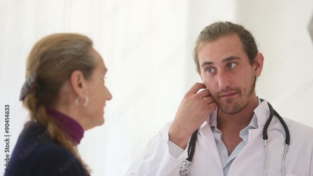 A male and young doctor speaking seriously with a female patient nodding A male and young doctor speaking seriously with a female patient nodding