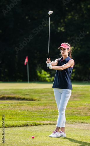 Playing golf, a woman looking at the green on the golf course