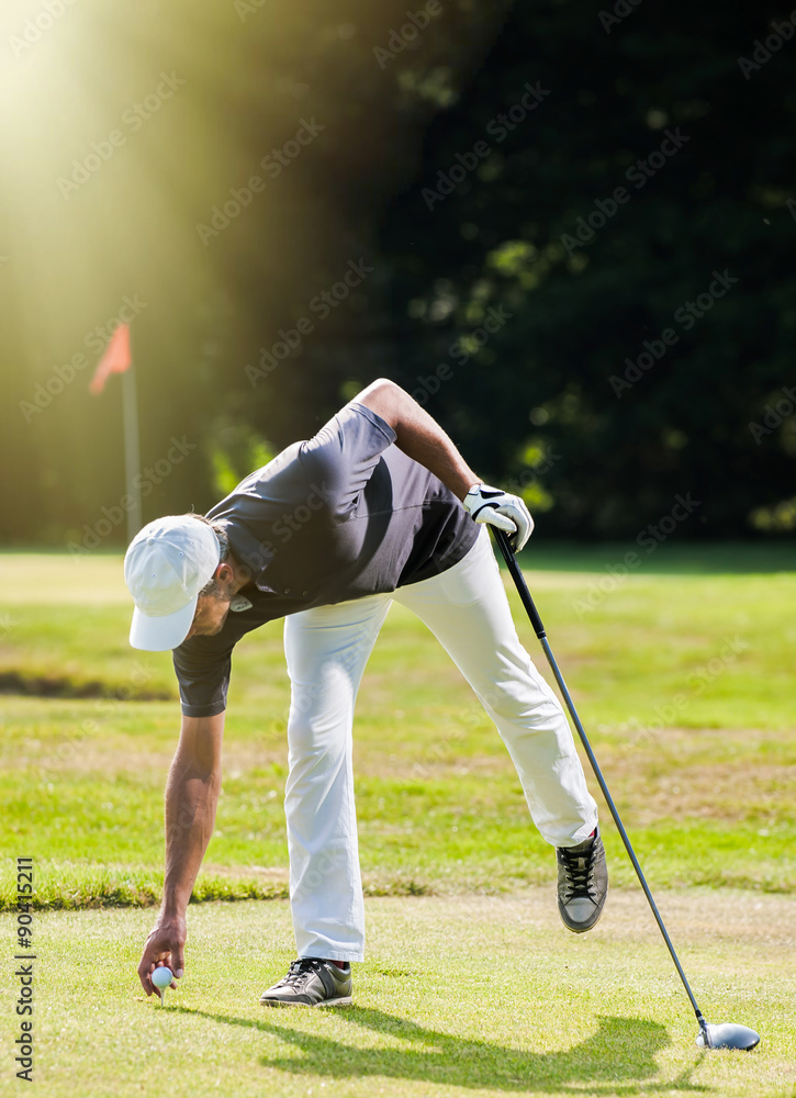 Obraz premium golfer putting his ball on the tee during a sunny afternoon