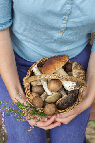 Girl holding a basket full of mushrooms in the hands