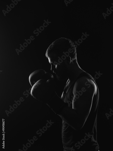 Athletic bearded boxer with gloves on a dark background
