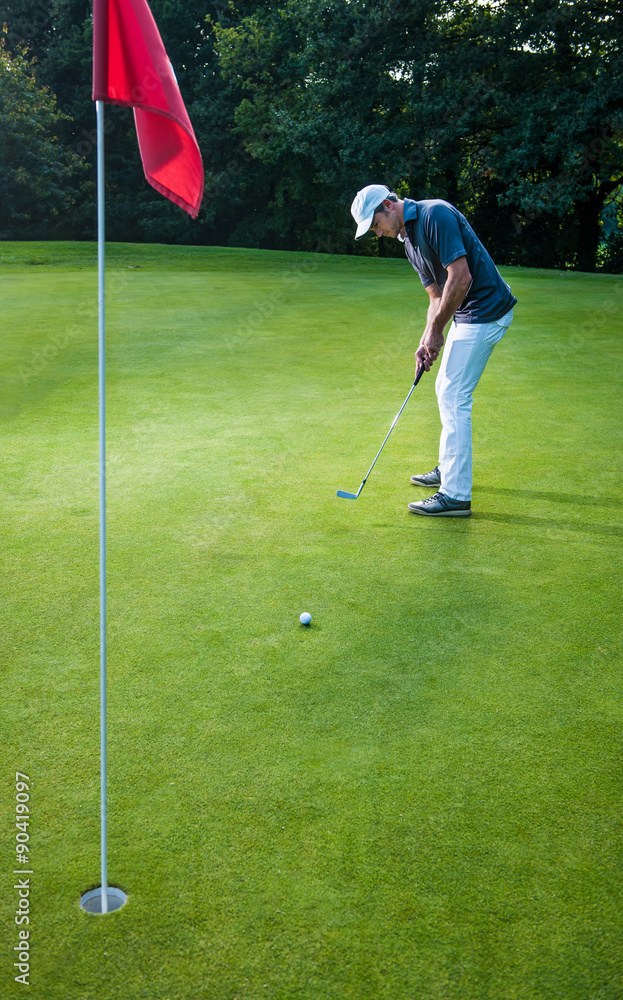 Obraz premium a man with a cap playing golf on a green field