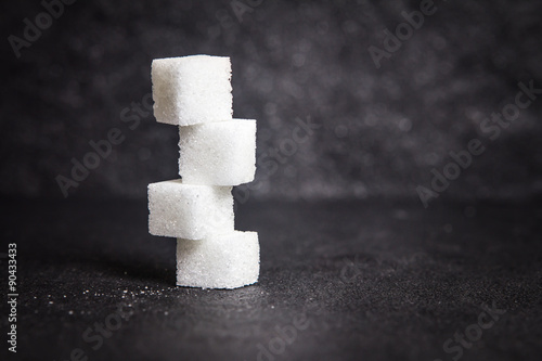 cloose up white sugar cubes on black stone plate background