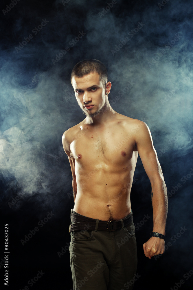 Portrait of a muscular male model against dark background with Portrait of a muscular male model against dark background with