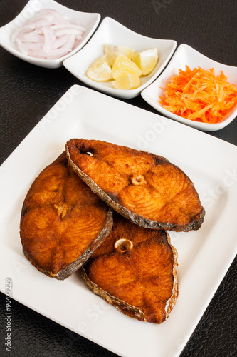 Картината върху платно Indian seer fish fillets fry - Closeup of delicious seer/mackerel fish fillets fry served with shredded carrots, raw onion rings, lemon