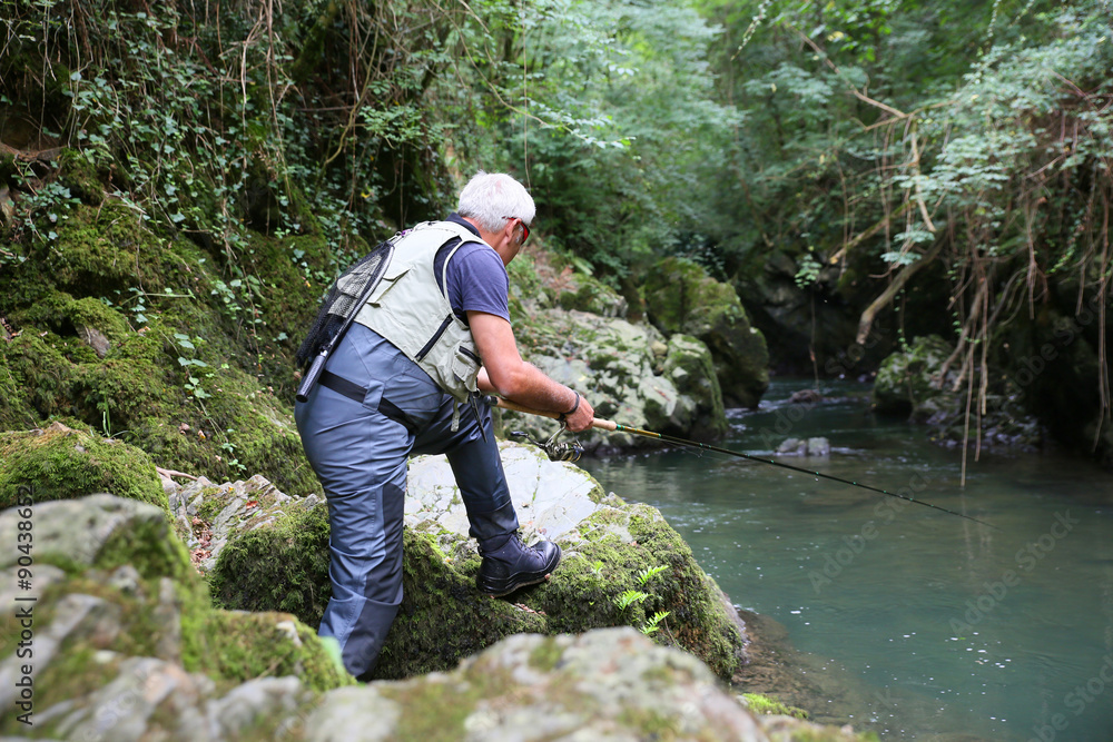 Fly-fisherman fishing in river on summer season Fly-fisherman fishing in river on summer season
