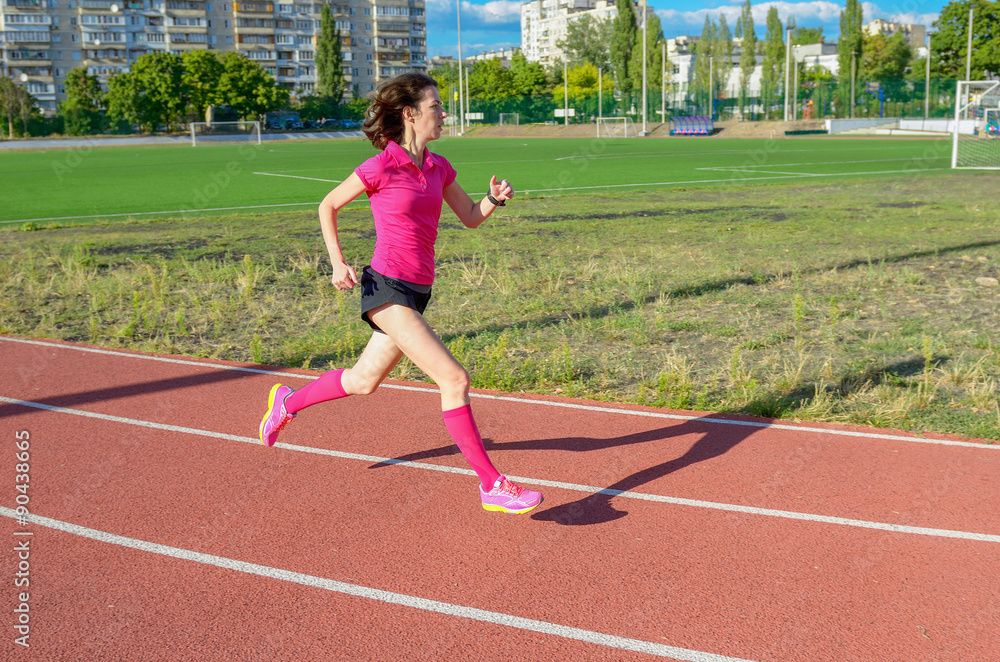 Happy active woman running on track, sprinting and working out on stadium

