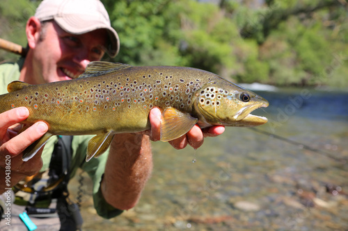 Fly-fisherman holding brown trout recently caught