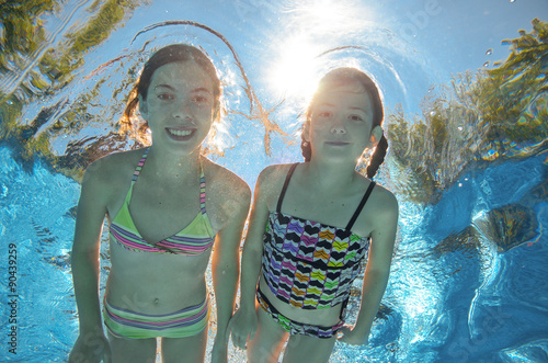 Children swim in pool or sea underwater, happy active girls have fun in water