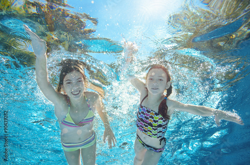Children swim in pool or sea underwater, happy active girls have fun in water