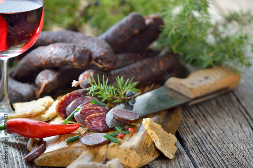 Südtiroler Brettljause mit deftigen Kaminwurzen und knusprigem Schüttelbrot, dazu ein Glas Südtiroler Rotwein photo